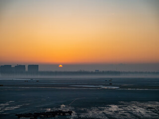 Obraz premium Sunset glows over airport tarmac with misty horizon.