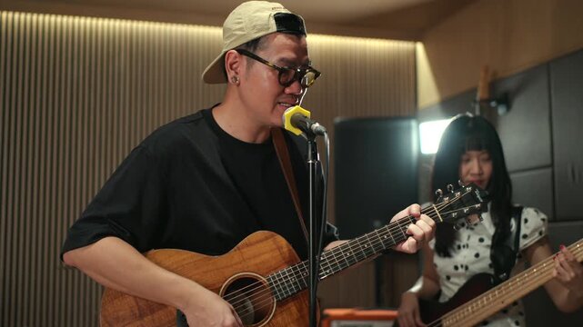Band musicians performing live professional in recording studio, practicing rehearsal session with vocals bassist and drummer teamwork, music production creative and energetic live performance.

