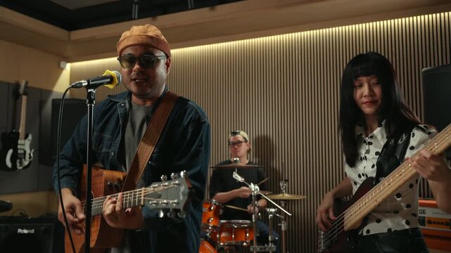 Band musicians performing live professional in recording studio, practicing rehearsal session with vocals bassist and drummer teamwork, music production creative and energetic live performance.
