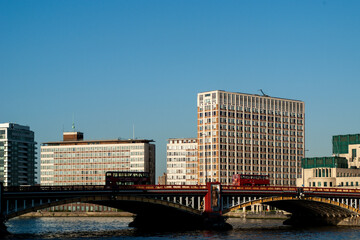 Red double-decker bus crossing vauxhall bridge over river thames