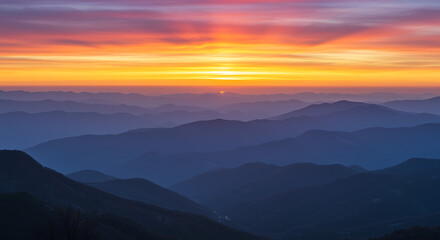 Obraz premium A serene mountainous landscape at dusk with vibrant sky colors and layered silhouettes.