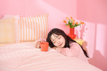 ピンク背景の部屋でリラックスするアジアの若い女性のポートレート