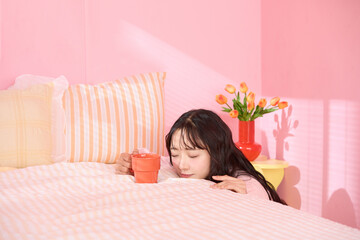 ピンク背景の部屋でリラックスするアジアの若い女性のポートレート