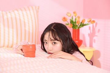 ピンク背景の部屋でリラックスするアジアの若い女性のポートレート