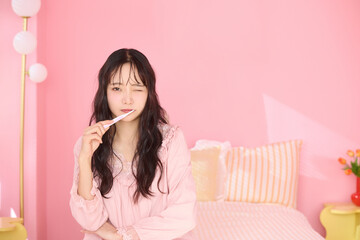 ピンク背景の部屋でリラックスするアジアの若い女性のポートレート