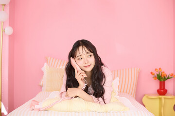 ピンク背景の部屋でリラックスするアジアの若い女性のポートレート