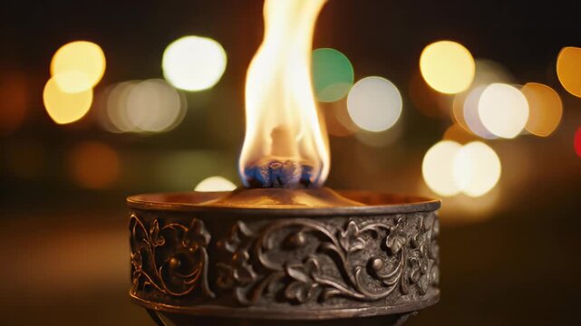 Close-up of a decorative torch burning brightly at night with blurred bokeh lights in the background
