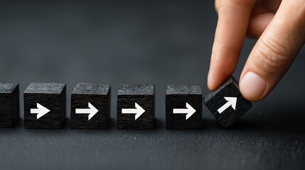 Individual hand places a wooden block with an upward arrow into a sequence of blocks pointing right