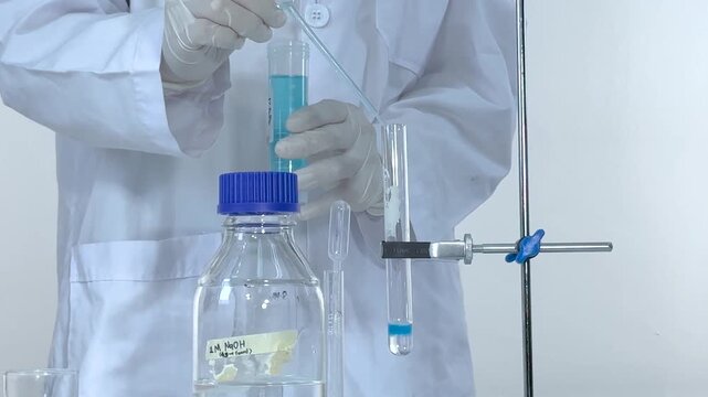 Chemist in Lab Coat Mixing Blue Liquid Solution in Test Tube