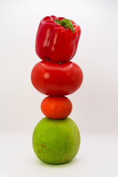 Mandarin, apple, tomato and sweet pepper in the form of a tower on a white background, the concept of healthy eating from fruits and vegetables, health care, fruit diet, vegans and vegetables. High qu