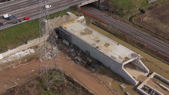 Aerial view of a concrete underpass construction next to a highway and railway