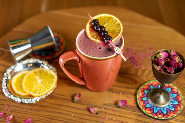 Cozy Berry Drink with Orange Garnish and Rosebuds on Wooden Table