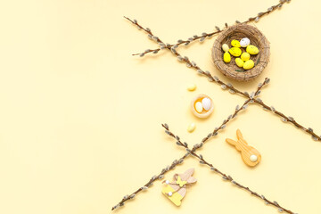 Fototapeta premium Nests with Easter eggs, wooden bunnies and pussy willow branches on yellow background