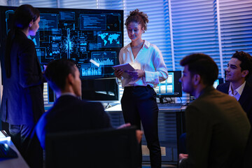 Confident businesswoman presenting global data analysis to team on large digital screen....