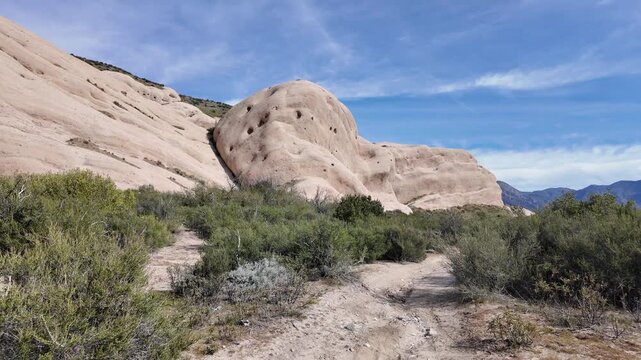 A Look at Mormon Rock in California and the sedimentary rock that makes it up with a woman geo,ogist inspecting the sediments for erosion factors