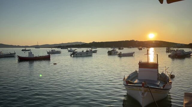 Paros Island,Footage over looking traditional Greek small fisherman's boats on sea towards the sinking sun and the hills at the back ground.No people.Tranquility.