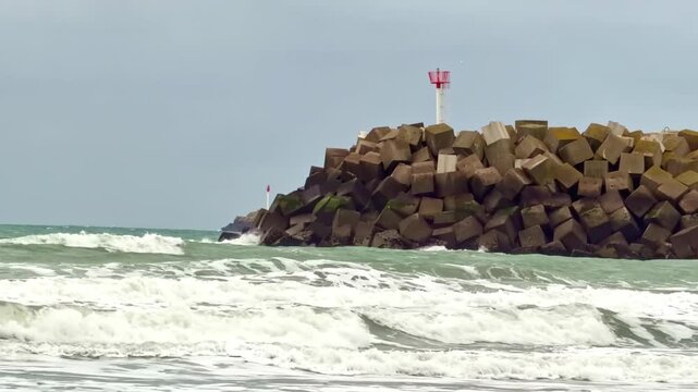Rough waves crashing against concrete breakwater in Saint-Jouin-Bruneval beach, Normandy in France.