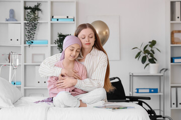 Obraz premium Little girl after chemotherapy with her mother hugging at hospital. Childhood cancer awareness concept