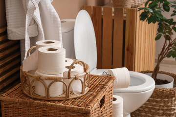Tray with toilet paper rolls on basket in restroom, closeup