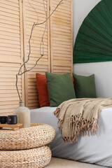 Interior of bedroom with folding screen, tree branches in vase and Chinese decor