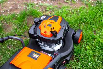 High angle view of a modern orange lawn mower engine on a green lawn. garden tools, lawn maintenance, yard work.