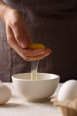 Close-up of woman's hands holding a fresh white organic egg, preparing for cooking in the kitchen