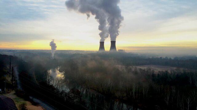 A nuclear facility at dawn, with the cooling towers billowing steam into the dawn sky. Camera motion is a slow jib up.