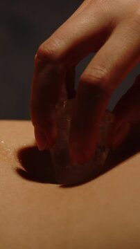 Beautiful vertical close up of an ice cube sensually caressing the belly and bellybutton of a pretty woman