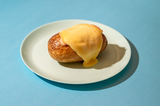 Raclette cheese with roasted potato on a blue plate