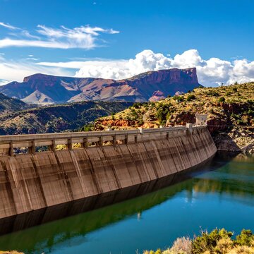 A concrete dam on a serene lake with mountains