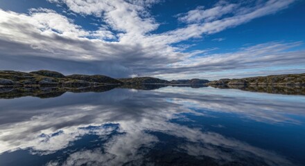 Fototapeta premium Lake reflects sky; rocky shore in distance