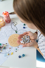 Astrologist hands holding numerology stones over natal charts and zodiac wheel