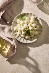 Mini mozzarella cheese balls with basil on light background, top view