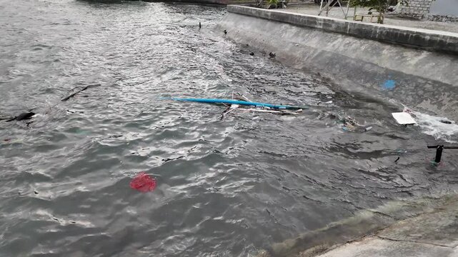 Slow-motion underwater shot of murky ocean water heavily contaminated with floating plastic waste, debris, and discarded packaging. 