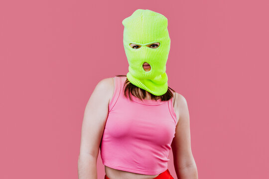 Woman wearing neon balaclava making a hand gesture