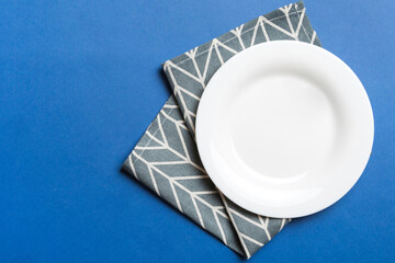 Top view on colored background empty round white plate on tablecloth for food. Empty dish on napkin with space for your design © sosiukin