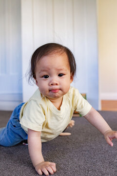 Asian girl crawling on carpeted floor inside home