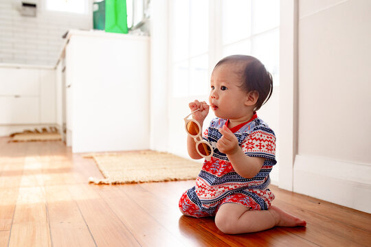 Asian baby girl playing with sunglasses on the wooden floor