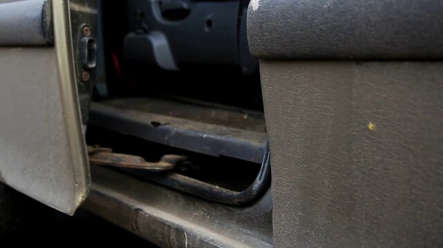 Motion sequence of vehicle door opening and closing, showing hinge and internal components. Dirty exterior surface of gray car. Focus on mechanical action and worn condition.