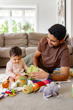 Indian dad playing with baby girl on the carpeted floor