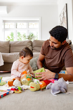 Indian dad playing with baby girl on the carpeted floor