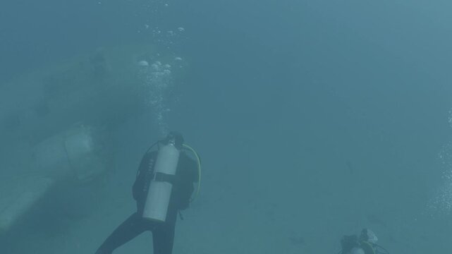 log footage of scuba divers  exploring an air craft wreck underwater. Ocean pollution. metal on ocean floor