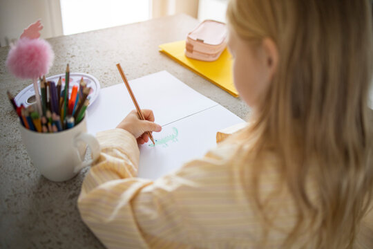 Over Shoulder View of Young Girl Drawing with Pencil at Home.