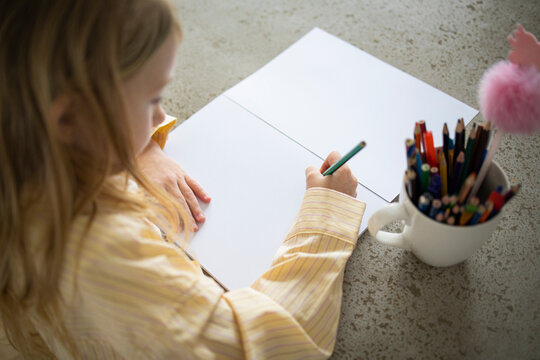 Over Shoulder View of Young Girl Drawing with Pencil at Home.
