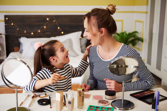 Mother and daughter applying make up together, using lipstick