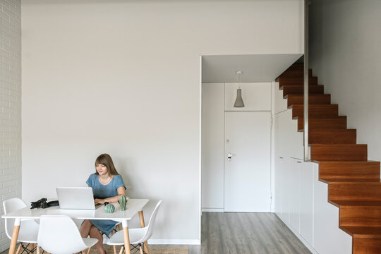 Woman sitting at table working on graphics tablet and laptop