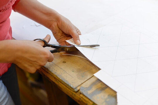 Close-up of woman cutting paper from draft in glazier's workshop