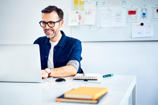 Casual businessman working on laptop at desk in office