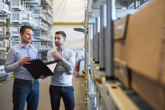 Two men standing in factory warehouse