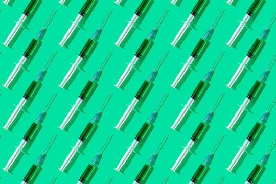 Multiple syringes organized in a pattern over green background